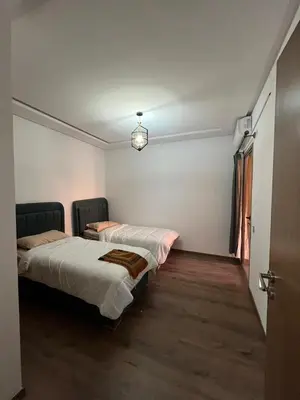 two beds in a small room with a door at Appartement moderne 5 min au centre de ville proche du gueliz in Marrakech