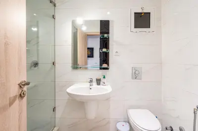 a white bathroom with a sink and a toilet at Sunny Luxe 2BR Heaven Apt Wi-Fi, Balcony & Pool in Marrakech