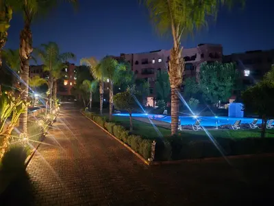 a street with palm trees and lights at night at Elegant Apartment in Marrakech Premium Village with Five Pools & Free Parking in Marrakech