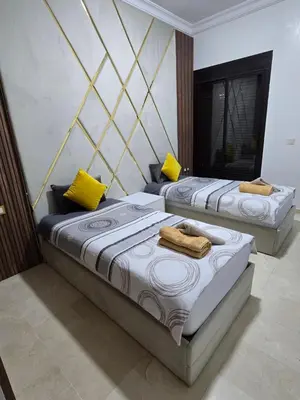 two beds in a room with yellow pillows at Elegant Apartment in Marrakech Premium Village with Five Pools & Free Parking in Marrakech