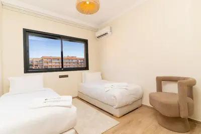 a room with a bed and a chair and a window at Luxury Apartment Hivernage 5 minutes from Jemaa El Fna in Marrakech