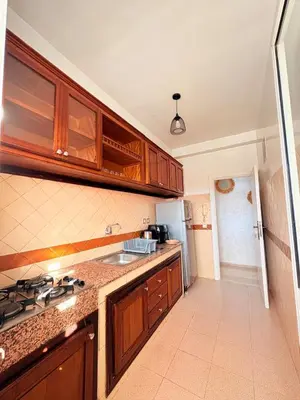 a kitchen with wooden cabinets and a sink and a refrigerator at A haven of light & sweetness in Marrakech