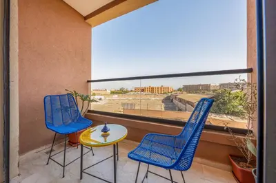 a balcony with two chairs and a table and a large window at Stylish Apartment with Balcony view & Free Parking in Marrakech