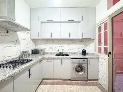 a kitchen with white cabinets and a washing machine at Havre de calme - Cour & 2 chambres in Marrakech