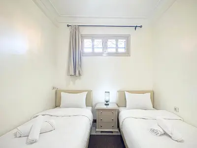 two twin beds in a room with a window at Havre de calme - Cour & 2 chambres in Marrakech