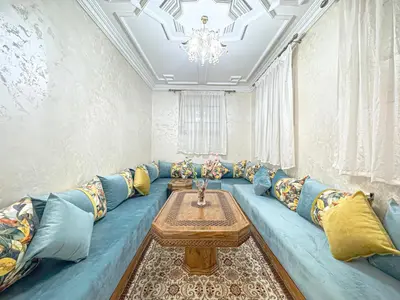 a living room with a blue couch and a table at Havre de calme - Cour & 2 chambres in Marrakech