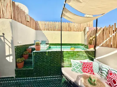 a patio with a hot tub and a fence at Riad des bibouches pool breakfast private in Marrakech