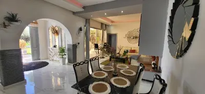 a dining table and chairs in a living room at Villa Maison Dar Sukar in El Caïd Omar