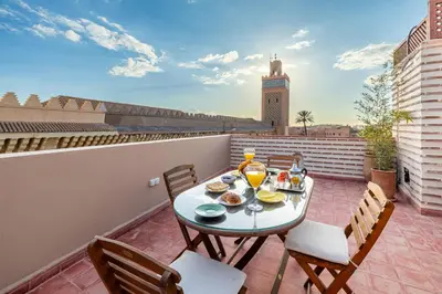 a balcony with a table and chairs on a roof at Riad Mimouna - Rooftop view & Breakfast included - 4 Rooms - Fully private in Marrakech