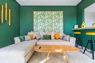 a living room with a white couch and a green wall at Charming 1-BR with Terrace, AC, Parking-City Center in Marrakech