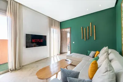 a living room with a white couch and a green wall at Charming 1-BR with Terrace, AC, Parking-City Center in Marrakech