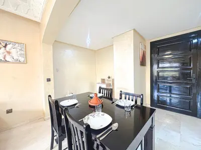 a dining room with a black table and chairs at Le Cosy Urbain - Proche centre, Parking & Balcon in Marrakech
