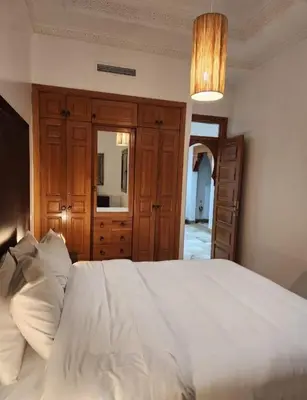 a bedroom with a white bed with a dresser and a mirror at Palmeraie Garden Luxury Appartement Family Only in Marrakech