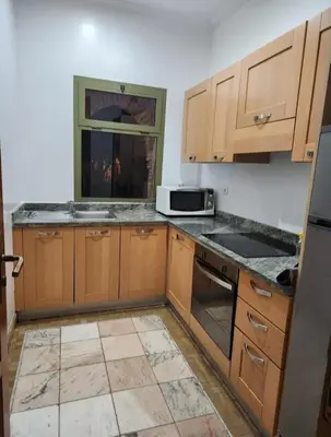 an empty kitchen with wooden cabinets and a microwave at Palmeraie Garden Luxury Appartement Family Only in Marrakech
