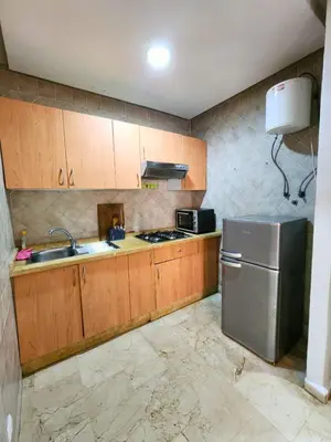 a kitchen with wooden cabinets and a stainless steel refrigerator at Caprice Palace Residence Bella Anima in Marrakech