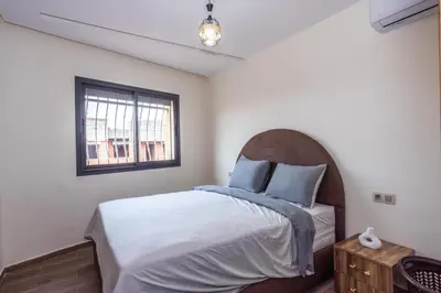 a bedroom with a bed with blue pillows and a window at Luxurious and Cozy Apartment with Parking and View in Marrakech
