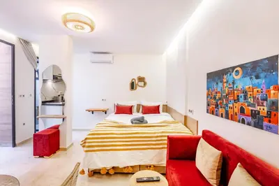 a bedroom with a bed and a red couch at Studio chic et cosy au cœur de Guéliz in Marrakech