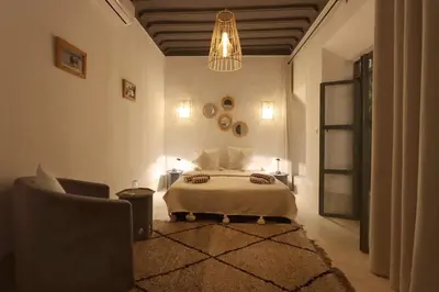a bedroom with a bed and a chair and a chandelier at RIAD BAB OUCHKA & Heated pool in Oulad Akkou