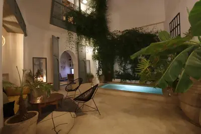 a living room with a pool with chairs and plants at RIAD BAB OUCHKA & Heated pool in Oulad Akkou