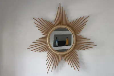 a gold sunburstburst mirror on a white wall at RIAD BAB OUCHKA & Heated pool in Oulad Akkou