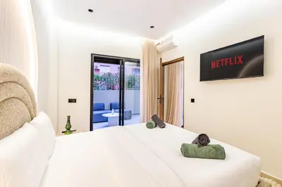 a bedroom with a white bed with a television on the wall at Le Nid de Guéliz Private terrace and silence in Marrakech