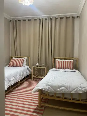 a bedroom with two beds and a curtain at Cozy flat near airport in Marrakech