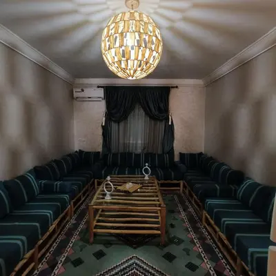 an empty room with green chairs and a chandelier at Cozy flat near airport in Marrakech