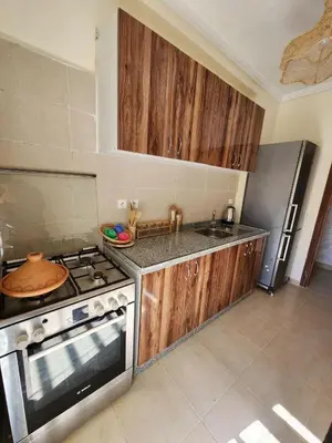 a kitchen with wooden cabinets and a stove top oven at Cozy flat near airport in Marrakech