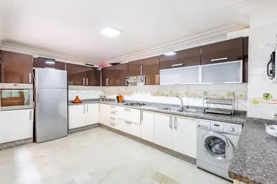 a kitchen with white cabinets and a washer and dryer at Oasis Familiale Marrakech Piscine & Résidence Sécurisée in Marrakech