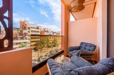 a balcony with two chairs and a large window at Gueliz Signature Terrasse and Comfort in Marrakech