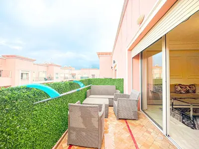 a patio with chairs and tables and a green hedge at Confort Signature - Piscine, balcon & parking in Marrakech