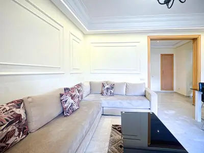 a living room with a couch and a table at Confort Signature - Piscine, balcon & parking in Marrakech
