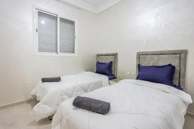 two beds with blue pillows in a room at Family apartment Jardins Chrifia in Marrakech