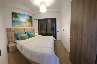 a bedroom with a large white bed with blue pillows at Appartement moderne confortable 2 chambres près de Marrakech Gueliz piscine in Marrakech