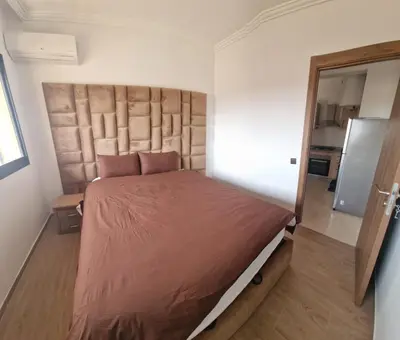 a bedroom with a large bed with a large headboard at Appartement moderne confortable 2 chambres près de Marrakech Gueliz piscine in Marrakech