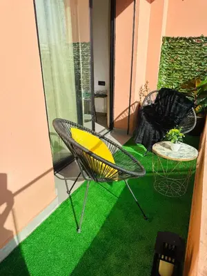 two chairs and a table on a balcony with green grass at Appartement Cozy Hivernage in Marrakech