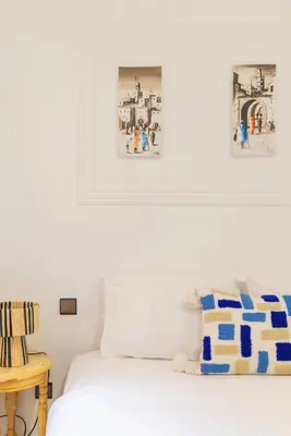 a bedroom with a white bed with a picture on the wall at Riad Qarya Petit-déjeuner et transfert inclus in Marrakech