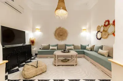 a living room with a blue couch and a tv at Riad Qarya Petit-déjeuner et transfert inclus in Marrakech