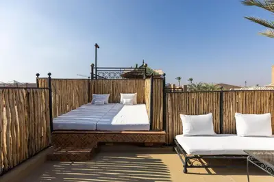 a balcony with two beds on a wooden fence at Riad Qarya Petit-déjeuner et transfert inclus in Marrakech