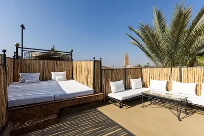 a patio with two beds and a bench on a deck at Riad Qarya Petit-déjeuner et transfert inclus in Marrakech