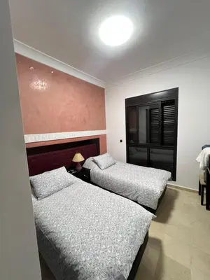 a bedroom with two beds and a table with a lamp at Quite place for your vacation in Marrakech