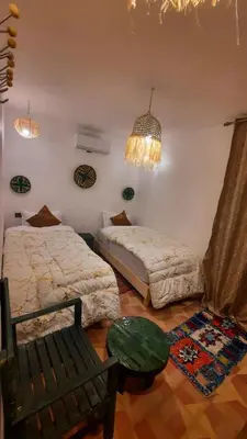a bedroom with two beds and a chair and a chandelier at Hotel & Riad Celia in Marrakech