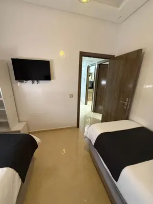 a bedroom with two beds and a flat screen tv at KSYI IMMO 4 Marrakech Aéroport in Marrakech