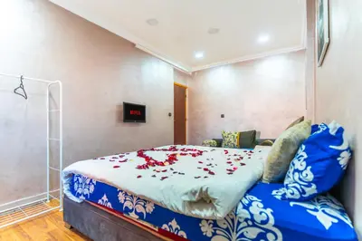 a bedroom with a bed with red flowers on it at Lely appartement 2min de là garé in Marrakech