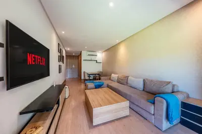 a living room with a couch and a flat screen tv at Magnifique appartement rez-de-jardin face piscine in Marrakech