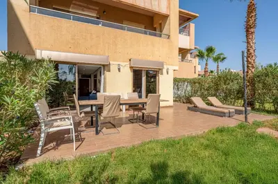 a patio with a table and chairs in front of a house at Prestigia Agate Appartement luxueux Marrakech golf city in Marrakech