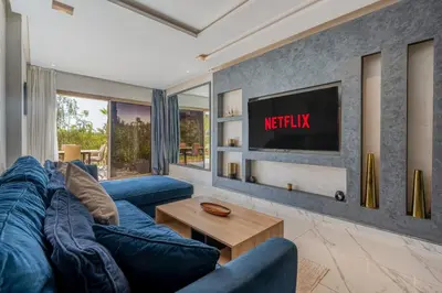 a living room with a blue couch and a tv at Prestigia Agate Appartement luxueux Marrakech golf city in Marrakech