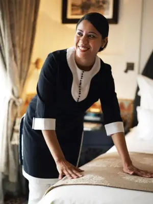 a woman is making a bed in a hotel room at Good Vibes - Hivernage Marrakech in Marrakech