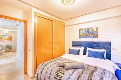 a bedroom with a large bed with a blue headboard at Appartement chic et confortable au cœur de Gueliz in Marrakech