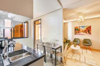 a kitchen with a sink and a table with chairs at Appartement chic et confortable au cœur de Gueliz in Marrakech